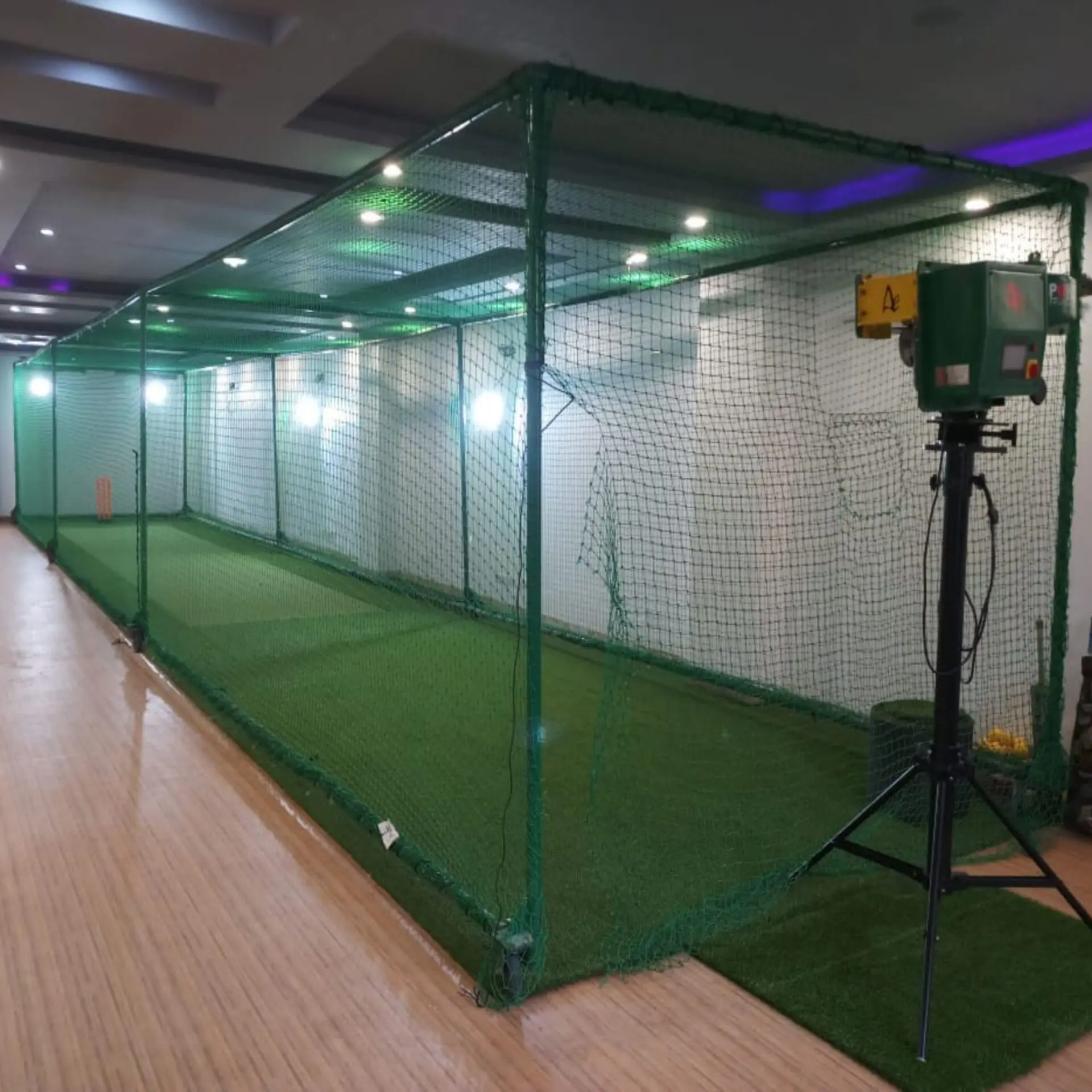 Ajaib Enterprises Indoor Cricket Practice Infrastructure: An indoor cricket cage featuring a bowling machine in the center.